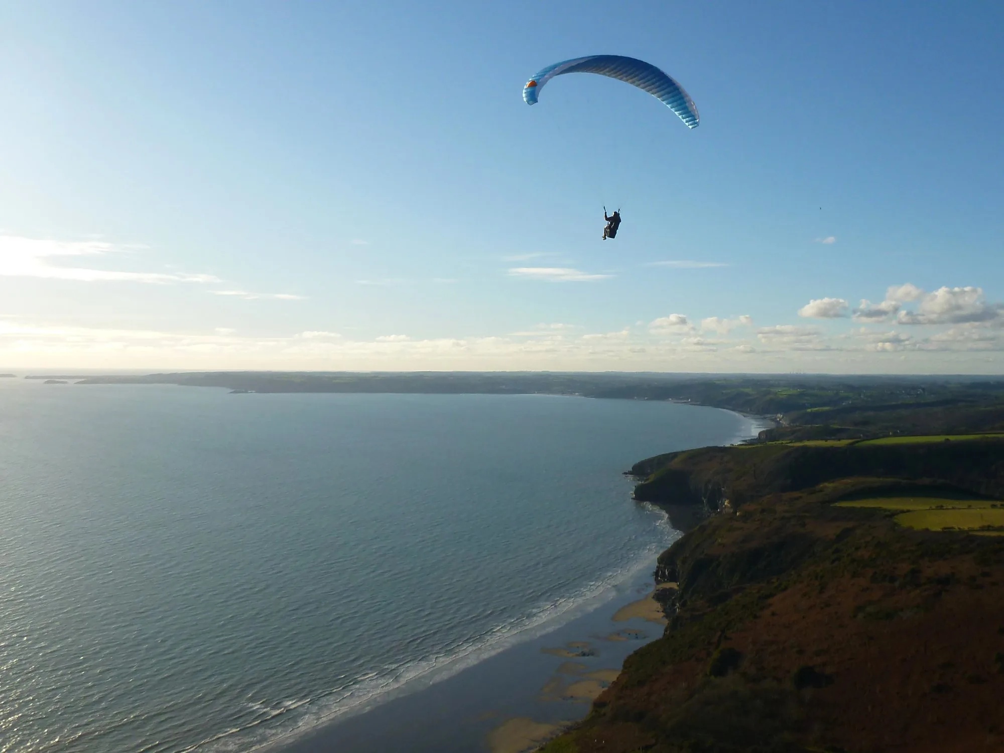 Paraglider soaring above the Pembrokeshire coast